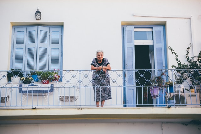 אישה זקנה נשענת על מעקה במרפסת